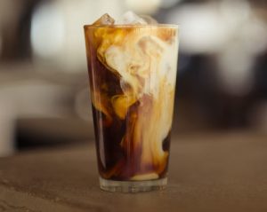 Milk and coffee slightly blending together in a glass.