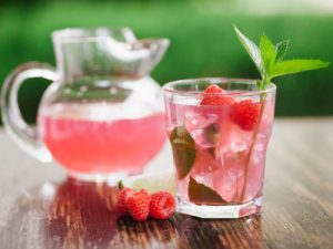 Refreshing raspberry mojito with limes, raspberries, and mint with a mint garnish.