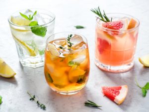 Summer refreshing fruit drinks with ice on a grey background.