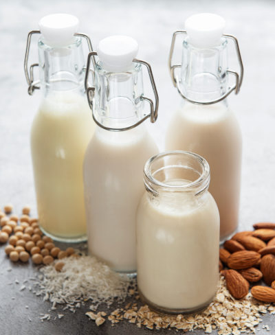Bottles with different plant milk - soy, almond and oat milk.