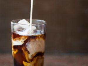 Iced cold brew coffee in a tall glass with cream poured over